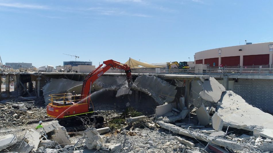 Orange excavator destroying part of the Cannington Carousel Shopping Centre as part of a Full demolition and strip out works