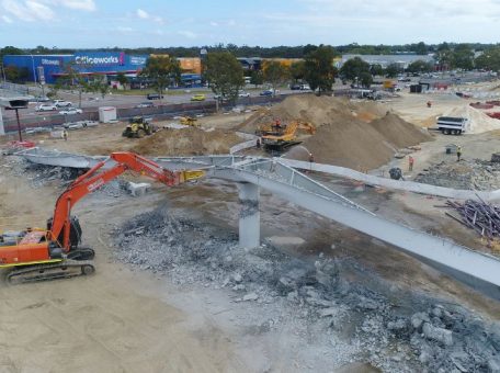 Wide shot of an orange excavator in Perth about to knock down a part of the carousel shopping center in Cannington, WA.