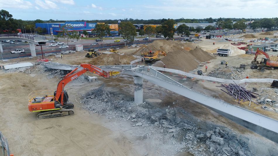 Wide shot of an orange excavator in Perth about to knock down a part of the carousel shopping center in Cannington, WA.